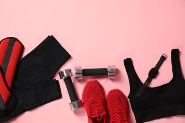 Farklı jimnastik malzemeleri ve pembe arka planda kol saati, düz yatış. Metin için boşluk