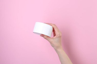 Pembe arka planda krema kavanozu olan kadın, yakın plan. Vücut bakımı ürünü