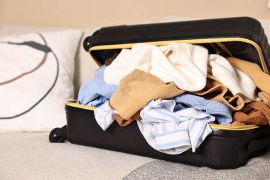 İçerideki kanepede farklı kıyafetlerle dolu bir bavul aç.