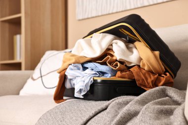 İçerideki kanepede farklı kıyafetlerle dolu bir bavul aç.