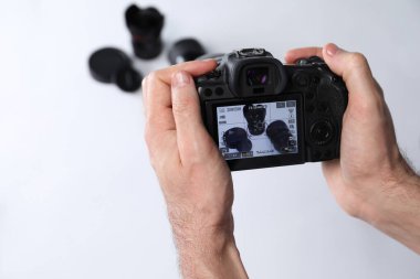 Fotoğrafçı, beyaz arka planda profesyonel kamerayla fotoğraf çekiyor, yakın plan. Metin için boşluk