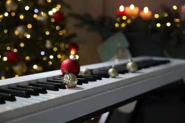 Elektrikli piyanonun üzerindeki Noel süsleri bulanık ışıklara karşı, yakın plan. Bokeh etkisi