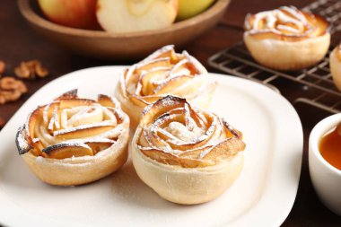 Ahşap masada servis edilen pudra şekerli elma gülleri, yakın plan.