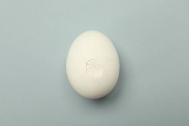 Gri arka planda kırık kabuklu bir yumurta, üst manzara.