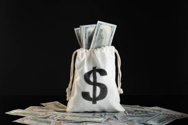 Siyah arka planda dolar banknotları olan çuval.