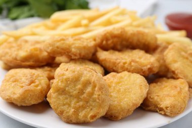 Lezzetli tavuk nugget ve patates kızartması beyaz masada, yakın plan.