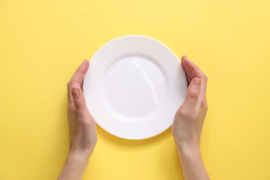 Sarı arka planda seramik plaka tutan kadın, üst manzara.