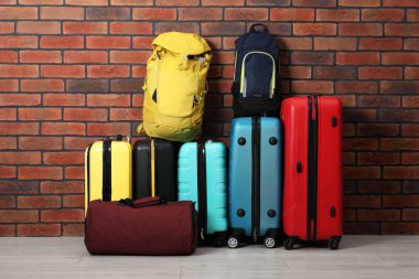 Duvarın yanında bir sürü renkli bavul, sırt çantası ve çanta var.