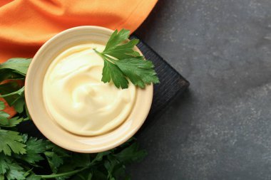 Lezzetli mayonez sosu kasede, gri masadaki maydanozla, üst manzara. Metin için boşluk