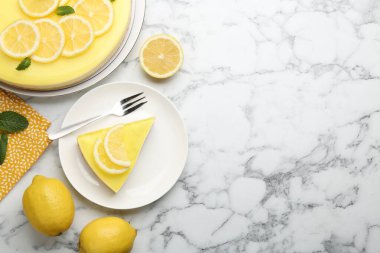 Lezzetli limonlu cheesecake, nane, narenciye meyvesi ve beyaz mermer masa üzerinde çatal, düz yatak. Metin için boşluk