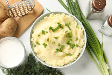 Beyaz mermer masada servis edilen yeşil soğanlı patates püresi.