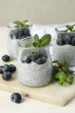 Yaban mersinli lezzetli chia pudingi ve nane şekeri ışıklı masada, yakın plan.