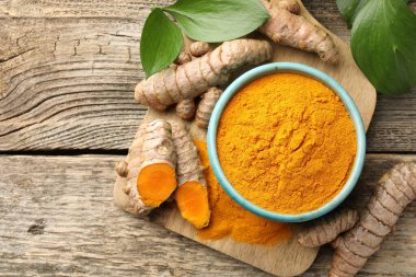 Kasede zerdeçal tozu, kökler ve yapraklar ahşap masada, düz yerde. Metin için boşluk