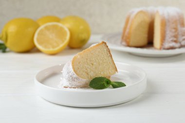 Lezzetli limonlu kek, pudra şekerli ve nane şekerli, beyaz ahşap masa, yakın plan.