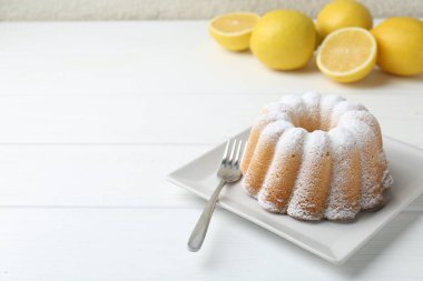 Beyaz ahşap masa üzerinde pudra şekerli ve çatallı lezzetli limonlu pasta, yakın plan. Metin için boşluk