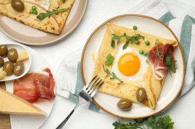 Yumurtalı leziz krepler, pastırma, zeytin ve roka beyaz masada, düz yerde.