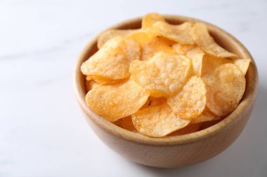Lezzetli patates cipsleri beyaz masada, yakın plan. Metin için boşluk
