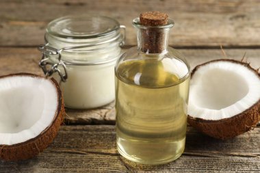 Organik hindistan cevizi pişirme yağı ve ahşap masada yarım meyve, yakın plan.