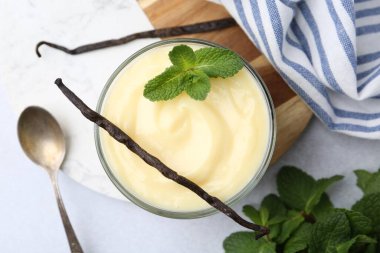Lezzetli vanilyalı puding, nane ve kapsüller açık gri masada, düz uzanmış