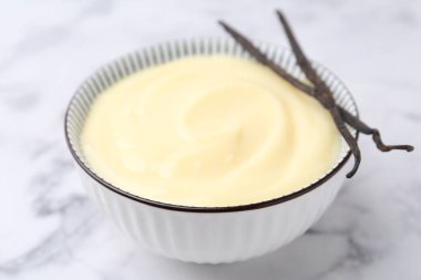 Lezzetli vanilyalı puding ve kapsüller beyaz mermer masada, yakın plan.