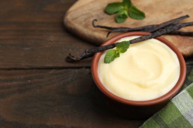 Lezzetli vanilyalı puding, nane ve kapsüller ahşap masada, yakın plan. Metin için boşluk