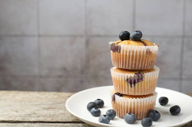 Ahşap masada yaban mersinli bir yığın leziz kek gri fayanslı arka planda, yakın plan. Metin için boşluk