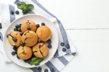 Yaban mersinli lezzetli kekler ve beyaz ahşap masa üzerinde nane şekeri, üst manzara. Metin için boşluk