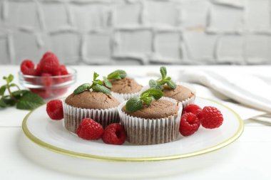 Ahududulu lezzetli kekler ve beyaz ahşap masa üzerinde nane şekeri ile gri desenli arka plan, yakın plan