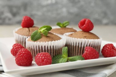 Gri masada ahududu ve nane şekerli lezzetli kekler, yakın plan.