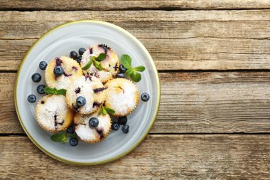 Yaban mersinli lezzetli çörekler, pudra şekeri ve ahşap masa üzerinde nane şekeri, üst manzara. Metin için boşluk