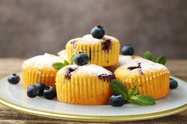 Yaban mersinli lezzetli çörekler, pudra şekeri ve nane şekeri, siyah arka planda, yakın planda.