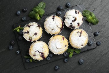 Yaban mersinli lezzetli çörekler, pudra şekeri ve siyah desenli masada nane şekeri.