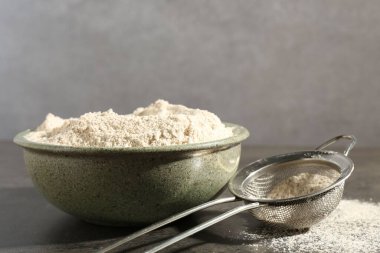 Kahverengi pirinç unu ve elek gri masada, yakın plan. Metin için boşluk