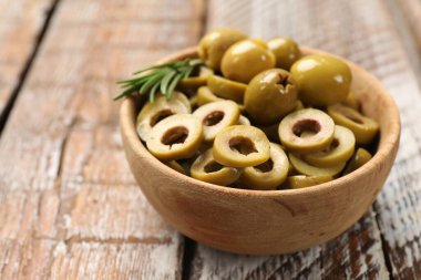 Lezzetli marine edilmiş zeytin halkaları, biberiye ve ahşap masadaki kasenin içindeki bütün halkalar, yakın plan.