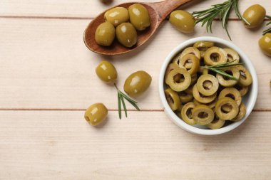 Lezzetli salamura edilmiş zeytin halkaları, kaşık dolusu ve biberiye açık ahşap masa üzerinde, düz uzanmış. Metin için boşluk