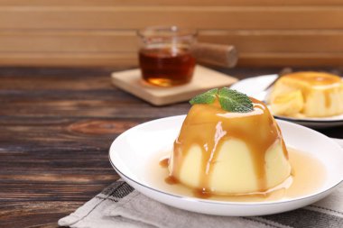 Karamel soslu lezzetli puding ve ahşap masada nane şekeri, yakın plan. Metin için boşluk