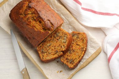 Beyaz ahşap masada fındıklı ve bıçaklı ev yapımı havuçlu kek.