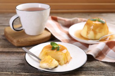 Karamel soslu lezzetli puding ve ahşap masada servis edilen nane.