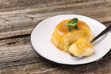 Karamel soslu lezzetli puding ve ahşap masada servis edilen nane şekeri, yakın plan. Metin için boşluk