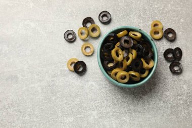 Gri desenli masa üzerinde farklı lezzetli marine edilmiş zeytin halkaları, düz yatış. Metin için boşluk