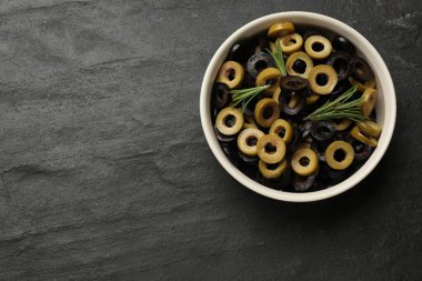 Farklı lezzetlerde marine edilmiş zeytin halkaları ve koyu dokulu masa üzerinde biberiye. Metin için boşluk