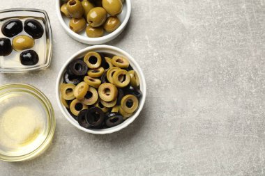 Farklı lezzetlerde marine edilmiş zeytin halkaları, hepsi ve gri desenli masa üzerindeki yağ, düz yatak. Metin için boşluk