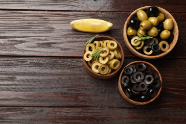 Farklı lezzetlerde marine edilmiş zeytin halkaları, bütün halkalar ve ahşap masa üzerinde biberiye, düz yatak. Metin için boşluk