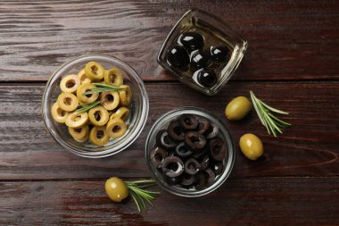 Farklı lezzetlerde marine edilmiş zeytin halkaları, bütün halkalar ve ahşap masa üzerinde biberiye, düz uzanış