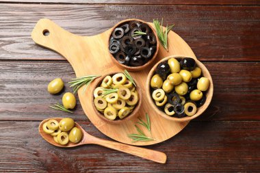 Farklı lezzetlerde marine edilmiş zeytin halkaları, bütün halkalar ve ahşap masa üzerinde biberiye, düz uzanış