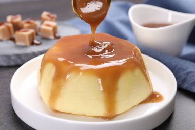 Gri masadaki pudingin üzerine karamel sosu dök.