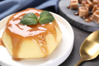 Gri masada servis edilen karamel soslu ve naneli lezzetli puding.