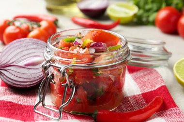 Kavanozda lezzetli salsa (Pico de gallo) ve ışık masasında malzemeler, yakın plan.