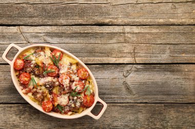 Peynirli, domatesli, kıymalı ve biberiyeli makarna güveci ahşap masada, üst manzara. Metin için boşluk