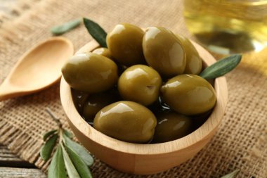 Lezzetli marine edilmiş zeytinler kasede ve yeşil yapraklar masada, yakın plan.